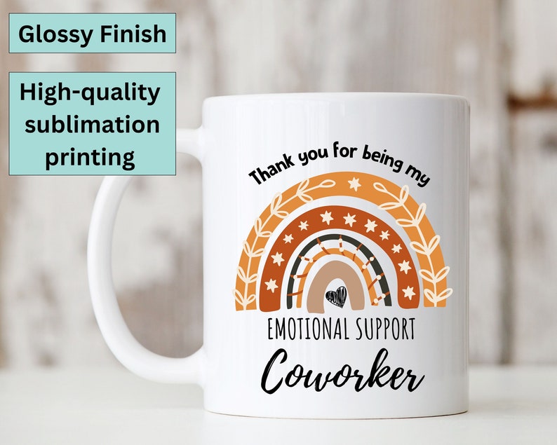 May include: White ceramic mug with a rainbow design and the text "Thank you for being my Emotional Support Coworker".