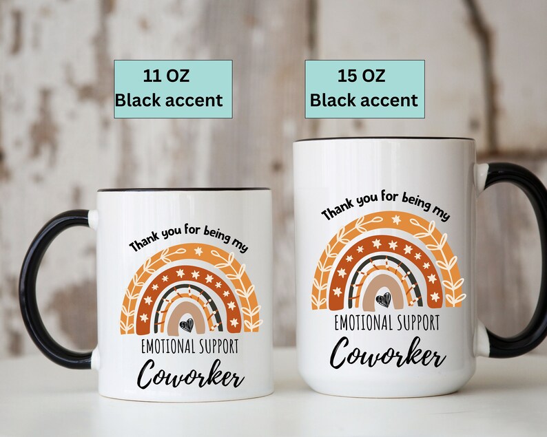 May include: White ceramic mug with a black rim and handle. The mug features a rainbow design with stars and the text "Thank you for being my Emotional Support Coworker". The mug is available in 11 oz and 15 oz sizes.