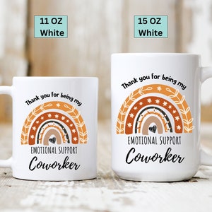 May include: White ceramic coffee mug with a rainbow design and the text "Thank you for being my Emotional Support Coworker".