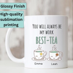 Pu&ograve; includere: Una tazza in ceramica bianca con un design verde e nero che presenta due tazzine da t&egrave; con facce e il testo "You will always be my work best-tea". I nomi "Emma" e "Leah" sono stampati sotto le tazzine da t&egrave;.