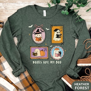 May include: Heather forest green long-sleeve shirt with a Halloween-themed graphic. The graphic features four framed illustrations of ghosts reading books, with bats and pumpkins. The text "BOOKS ARE MY BOO" is printed below the illustrations.