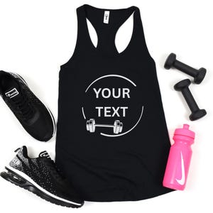 May include: A black racerback vest top featuring a white circular graphic with the text YOUR TEXT and a barbell icon. The vest top is surrounded by two black athletic trainers, two small black dumbbells, and a bright pink plastic water bottle.