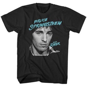 May include: Black t-shirt with a black and white portrait of Bruce Springsteen. The text "Bruce Springsteen" is in light blue above the portrait, with "The River" in light blue below a small graphic.