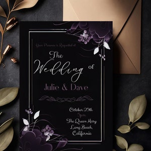 May include: A black wedding invitation with white and purple floral accents. The text reads "The Wedding of Julie & Dave" with the date, time, and location: October 25th, 5pm, The Queen Mary, Long Beach, California. A tan envelope is behind the invitation.