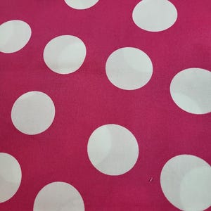 May include: Pink fabric with a white polka dot pattern.