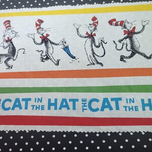 May include: Fabric featuring a repeating pattern of the Cat in the Hat characters in motion, with red bow ties and striped hats. The text "The Cat in the Hat" is displayed in blue and white. The design includes stripes and polka dots.