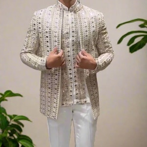 Può includere: Un blazer bianco con un design a specchio e una camicia bianca con colletto sotto. Il blazer ha un colletto alla coreana e una chiusura con bottone.