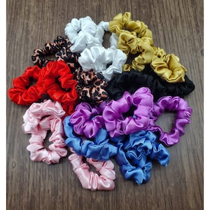 May include: A collection of colorful satin scrunchies in various colors, including red, white, purple, blue, pink, black, and leopard print.