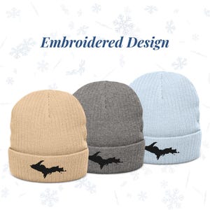 Può includere: Tre berretti a maglia a coste beige, grigio e azzurro. Ogni berretto presenta un design ricamato nero. Il testo "Embroidered Design" è sopra i berretti. Abbigliamento invernale.
