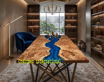 May include: A rectangular dining table featuring a live-edge burl wood surface with a central blue resin river inlay. The table has a geometric gold-toned metal base and displays the text Craftmen international on the surface.