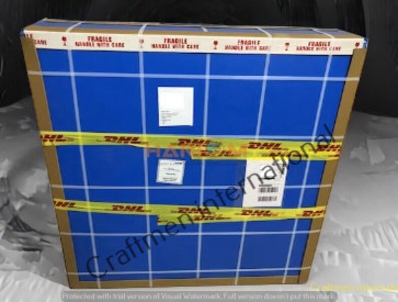 May include: A blue cardboard box with the words "FRAGILE HANDLE WITH CARE" printed on all sides. The box is taped with yellow tape that has the DHL logo printed on it. The text "Craftmen International" is printed on the bottom of the box.