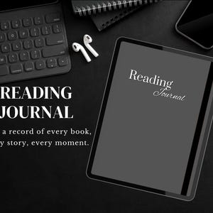 May include: A black tablet displaying "Reading Journal", with a keyboard, earbuds, and a pen. The text "Keep a record of every book, every story, every moment" is also visible. The items are arranged on a dark surface, creating a minimalist aesthetic.