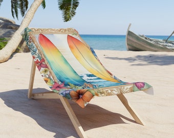 May include: A wooden beach chair with a colorful beach towel featuring two surfboards in a watercolor style. The towel has a floral border with red, pink, and orange flowers. The background shows a beach, ocean, and a boat.