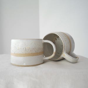 Wheel thrown pottery coffee mug, handcrafted, featuring brown and white glaze, perfect for rustic home decor.
