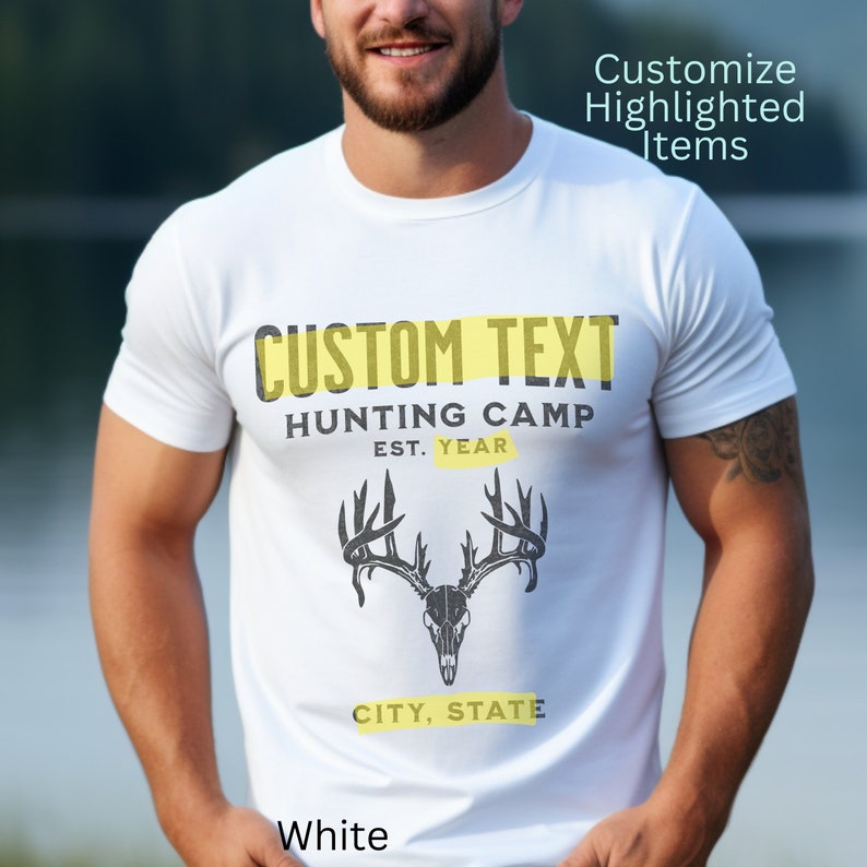 May include: White t-shirt with a black and white deer skull graphic and the text "CUSTOM TEXT HUNTING CAMP EST. YEAR CITY, STATE". The text "CUSTOM TEXT" is highlighted in yellow.