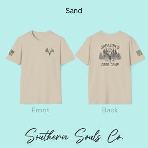 May include: Sand-colored t-shirt with a deer antler graphic on the front and a "Jackson's Deer Camp" design on the back. The shirt includes the text "Southern Souls Co." and an American flag design on the sleeve.
