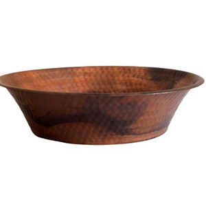 May include: A large, hammered copper bowl with a rounded bottom and a slightly flared rim. The bowl has a warm, reddish-brown patina.