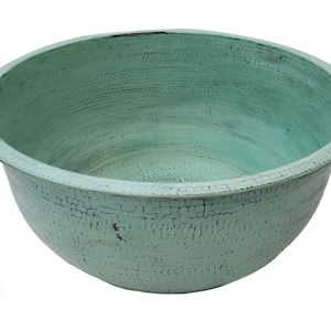 Puede incluir: Un cuenco grande, redondo, de cobre verde con un acabado martillado. El cuenco está vacío y tiene una pátina verde claro.