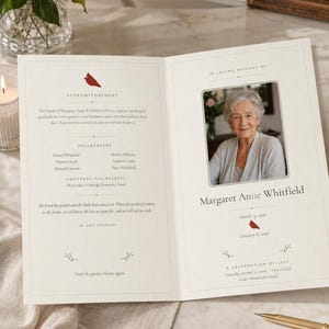 May include: A folded funeral program for Margaret Anne Whitfield featuring a cream-colored cardstock, a photograph of an older woman, and red cardinal bird illustrations. The text includes an acknowledgement, pallbearers, and service details.