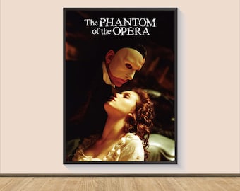 May include: A framed poster featuring a scene from "The Phantom of the Opera." The image shows a man in a mask looking down at a woman. The title of the movie is printed in white at the top of the poster.