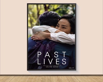 May include: Movie poster for the film "Past Lives" featuring Greta Lee, Teo Yoo, and John Magaro. The poster shows the two main characters embracing in a warm hug. The title of the film is written in large, bold letters below the image.
