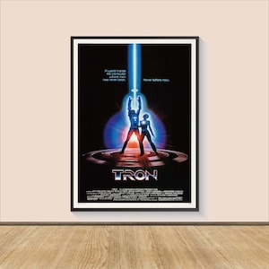 May include: A movie poster for the 1982 film "TRON". The poster features a blue and white image of two figures standing on a circular platform with a glowing blue light behind them. The text "TRON" is in large, white letters at the bottom of the poster.