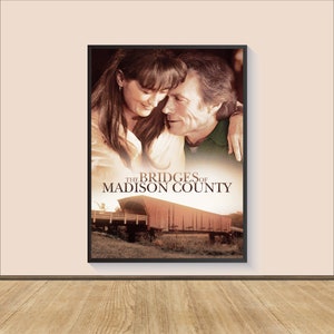 Può includere: Un poster del film "I ponti di Madison County" con una coppia che si guarda con un ponte coperto rosso sullo sfondo.