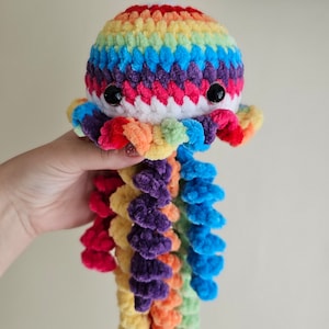 May include: A rainbow crocheted octopus plush toy with a white body and long, colorful tentacles.