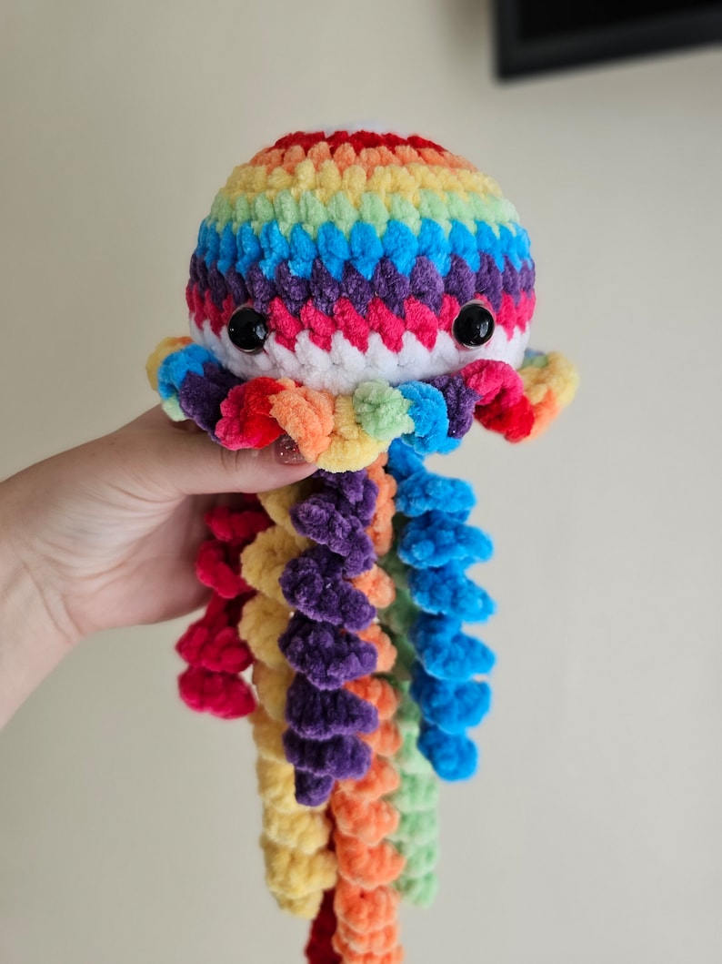May include: A rainbow crocheted octopus plush toy with a white body and long, colorful tentacles.