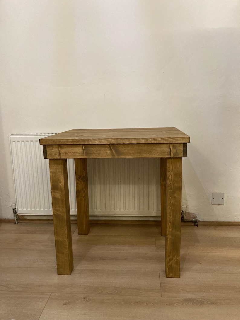 K&ouml;nnte beinhalten: Ein rustikaler Holztisch mit brauner Beize. Der Tisch hat eine rechteckige Tischplatte und vier Beine. Der Tisch steht auf einem hellen Holzboden.