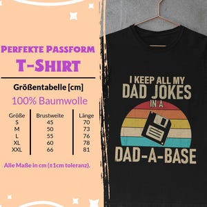 Peut inclure: T-shirt noir avec l'inscription "I KEEP ALL MY DAD JOKES IN A DAD-A-BASE" en blanc et beige. Le design comprend un coucher de soleil rétro et un graphique de disquette. Un tableau des tailles en cm est également visible.
