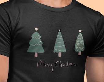 Könnte beinhalten: Schwarzes T-Shirt mit drei grünen Weihnachtsbäumen, die jeweils mit einem Stern gekrönt sind und braune Stämme haben. Die Worte "Merry Christmas" sind darunter in Kursivschrift geschrieben. Das Shirt besteht aus einem weichen Material.