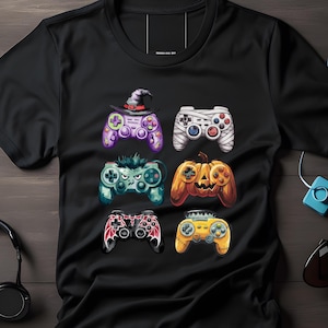 Könnte beinhalten: Schwarzes T-Shirt mit einem Design aus sechs verschiedenen Videospielcontrollern, die mit Halloween-Motiven verziert sind. Die Controller sind mit einem Hexenhut, einer Mumie, einem Kürbis, einem Monster, einer Fledermaus und einem Schädel verziert.