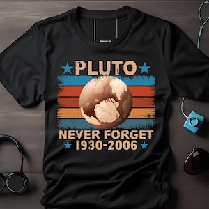 Könnte beinhalten: Schwarzes T-Shirt mit Retro-Design mit Pluto, einer braunen Planetengrafik und dem Text "PLUTO NEVER FORGET 1930-2006" in Weiß und Blau. Das Design enthält blaue und orangefarbene Streifen.