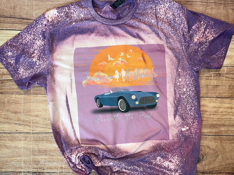 May include: Purple and white tie-dye t-shirt with a graphic featuring a blue convertible car, a sunset, and the text "Jackson & Blakely Beneath the Hood."