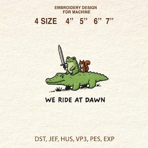 Può includere: Design per ricamo con un alligatore verde con una rana con una spada e uno scoiattolo. Il testo "WE RIDE AT DAWN" è sotto l'immagine. Dimensioni disponibili: 10 cm, 13 cm, 15 cm e 18 cm.