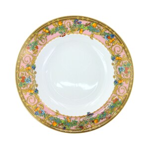 Puede incluir: Un plato de cena de cer&aacute;mica rosa y dorado con un dise&ntilde;o floral y frutal. El plato tiene un centro blanco y un borde decorativo con un patr&oacute;n repetitivo de flores, hojas y frutas.