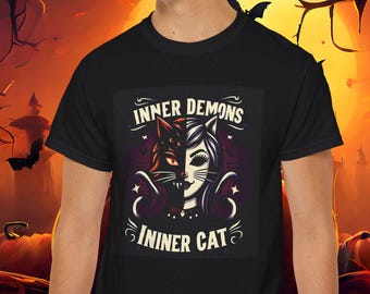 May include: Black t-shirt with a graphic design of a woman with a cat head. The graphic has the text "Inner Demons Inner Cat" in a vintage style font.