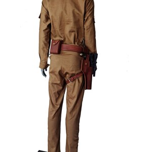 May include: A tan jumpsuit with a brown leather belt and a holster for a weapon. The jumpsuit has a collared shirt and long sleeves.