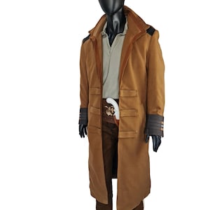 May include: A long brown coat with a high collar and a belt. The coat has a brown suede lining and black trim on the cuffs. The coat is worn over a light brown shirt and brown pants.