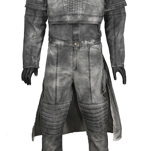 May include: A grey jumpsuit with a long, flowing cape. The jumpsuit has a high collar and a fitted bodice. The cape has a decorative trim around the edges.