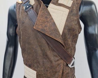 May include: A brown leather vest with a white and brown fabric panel on the front. The vest has a yellow strap with a black buckle and a brown strap with a silver buckle.