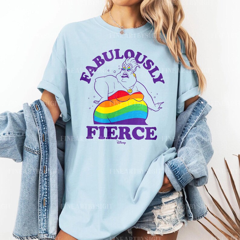 Peut inclure: T-shirt bleu clair avec un motif d'Ursula de La Petite Sir&egrave;ne de Disney. Le design comprend les mots "FABULOUSLY FIERCE" en violet, avec Ursula portant une robe arc-en-ciel. Le logo Disney est en bas.