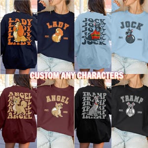 May include: Collection of sweatshirts featuring cartoon dog characters. Designs include "Lady", "Jock", "Angel", and "Tramp", with text and illustrations. The sweatshirts come in various colors, including navy, burgundy, black, and light blue.