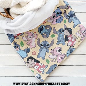 Puede incluir: Una manta beige con un patr&oacute;n repetido del personaje Stitch de la pel&iacute;cula Lilo & Stitch. La manta tiene un forro de sherpa blanco y esponjoso. La manta est&aacute; doblada en una cesta.