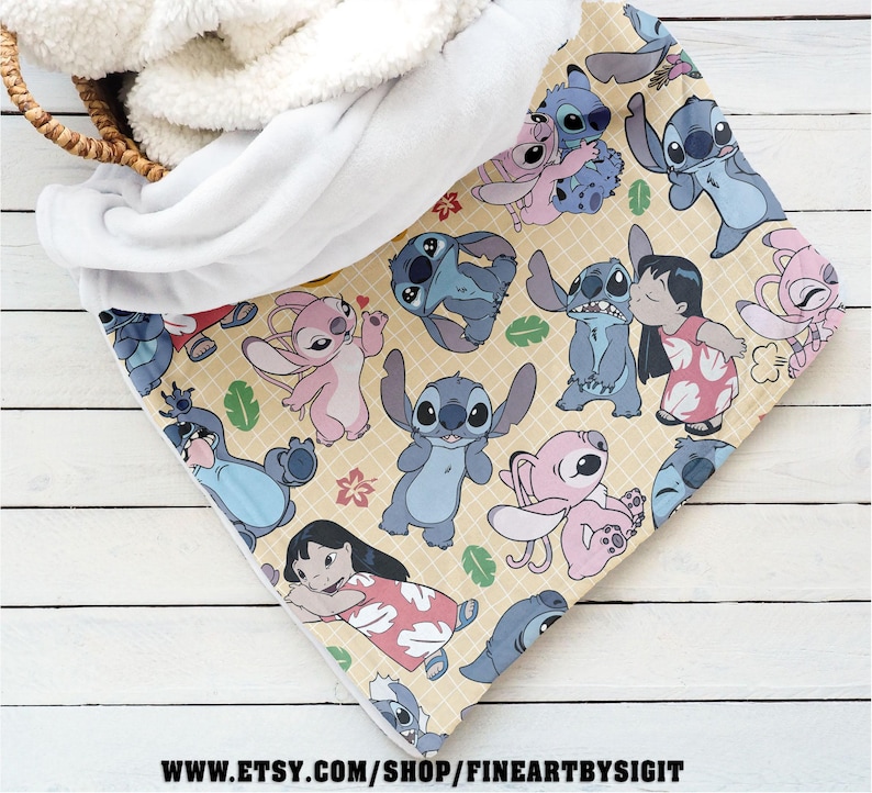 Puede incluir: Una manta beige con un patr&oacute;n repetido del personaje Stitch de la pel&iacute;cula Lilo & Stitch. La manta tiene un forro de sherpa blanco y esponjoso. La manta est&aacute; doblada en una cesta.