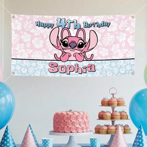 Op de afbeelding: Een roze en witte banner met de tekst "Happy 4th Birthday Sophia" en een stripfiguur. De banner is versierd met een bloemenpatroon en een blauwe rand. Een roze taart en cupcakes worden tentoongesteld.