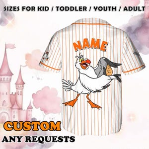 May include: White and orange striped baseball jersey with a cartoon seagull graphic and the word "NAME" printed on the back. The jersey is customizable.