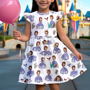 May include: A white dress featuring a repeating pattern of a cartoon princess in a purple gown, along with animal companions. The dress has short sleeves and a flared skirt. A pink balloon is held in the child's hand.