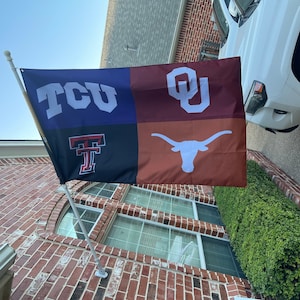 May include: A multi-colored flag with four sections. The top left section is blue with white letters that say "TCU". The top right section is maroon with white letters that say "OU". The bottom left section is black with a red "T" and the bottom right section is orange with a white longhorn steer.